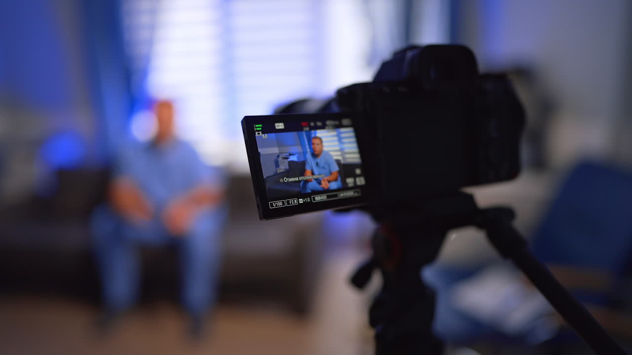 Caucasian man in blue uniform recording video. Doctor creating content for his vlog. Selective focus