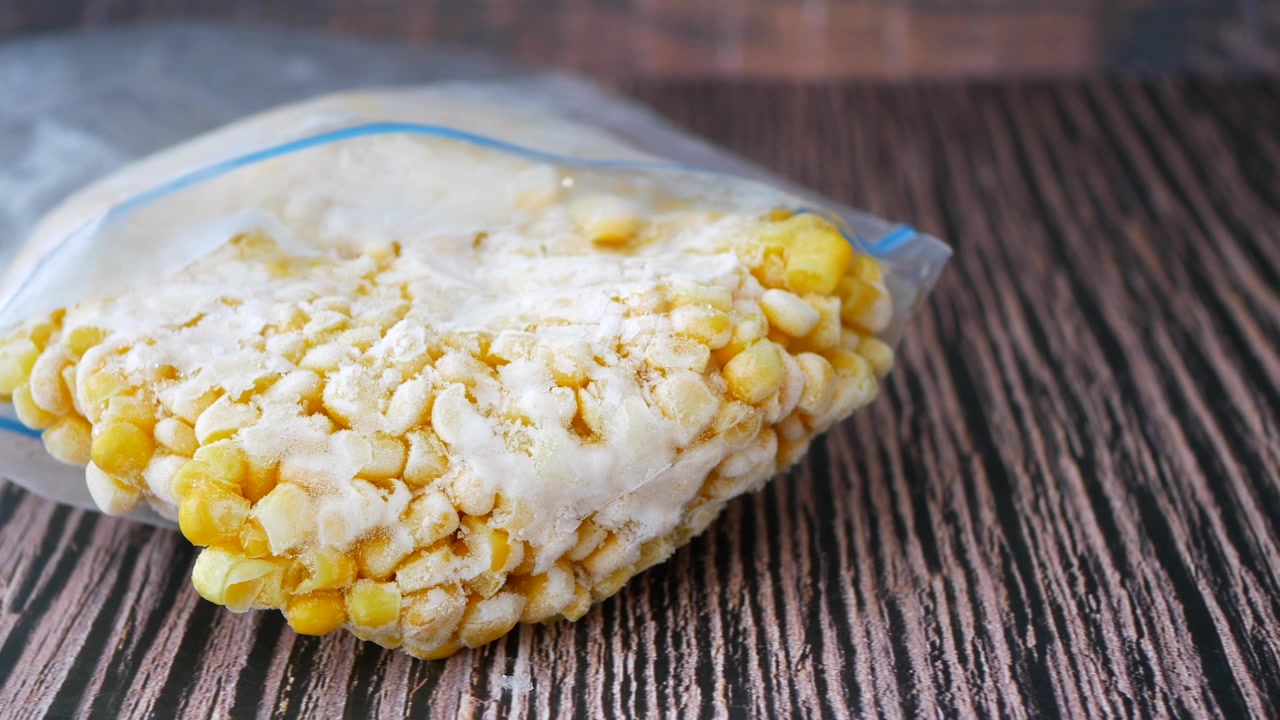 Grains de maïs surgelés dans un sac de conservation en plastique sur une table en bois
