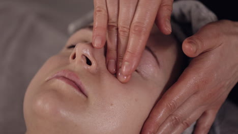 terapeuta de cosmetología haciendo mujer relajante spa masaje facial con las manos en el salón de desintoxicación y curación