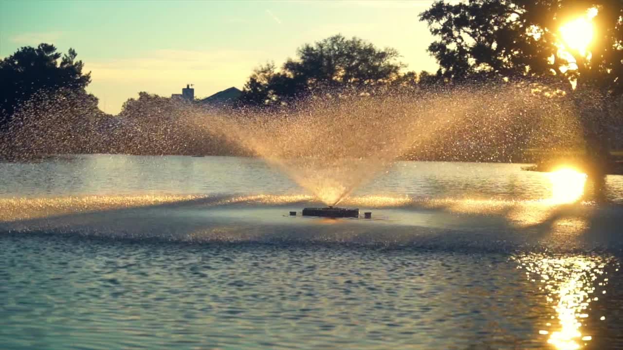 Sunset over a tranquil pond with a water fountain