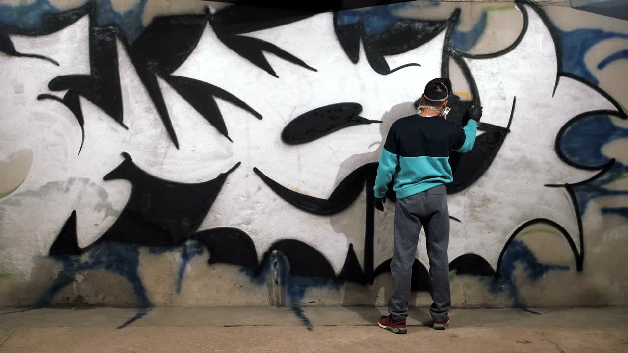 Graffitaro che dipinge sul muro della metropolitana