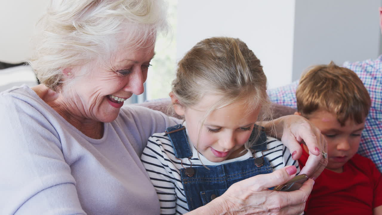 Nonna che gioca a un videogioco con la nipote sul telefono cellulare a casa