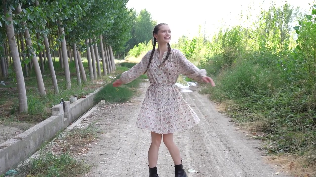 Una donna cammina tranquillamente lungo un sentiero polveroso splendidamente circondato dalla natura