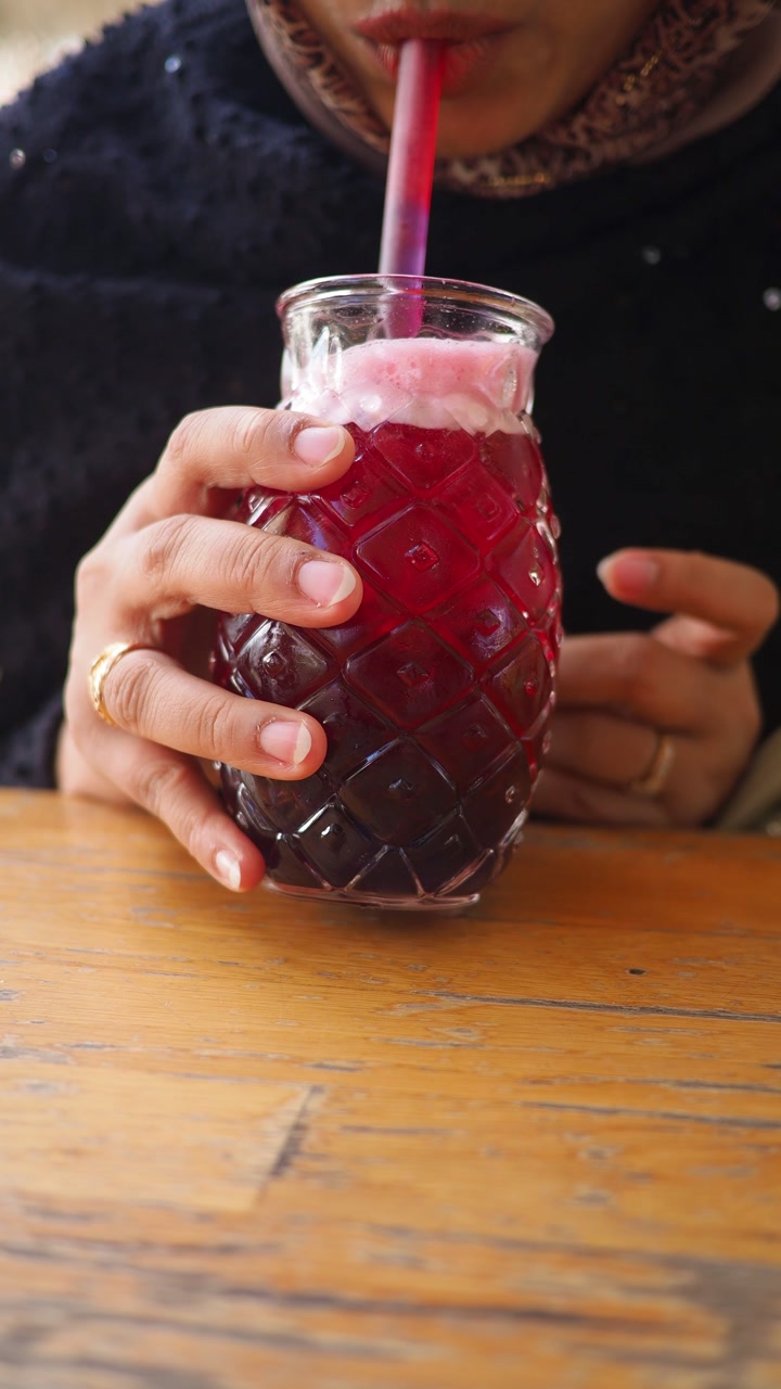Person Sipping a Vibrant Layered Drink with a Straw