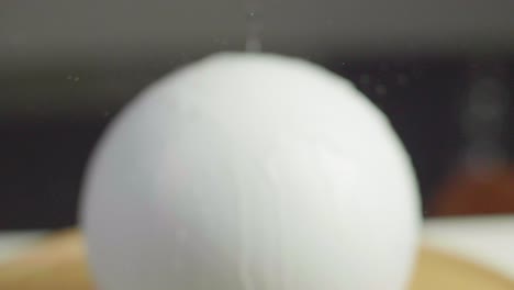 close up of water running on a white plain sphere wet. a dark gray background. shot in slow motion in 4k. fixed focus with backwards camera movement