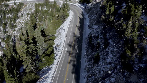 Snowing-over-an-empty-Curve-road-in-the-snow-covered-mountains-and-trees