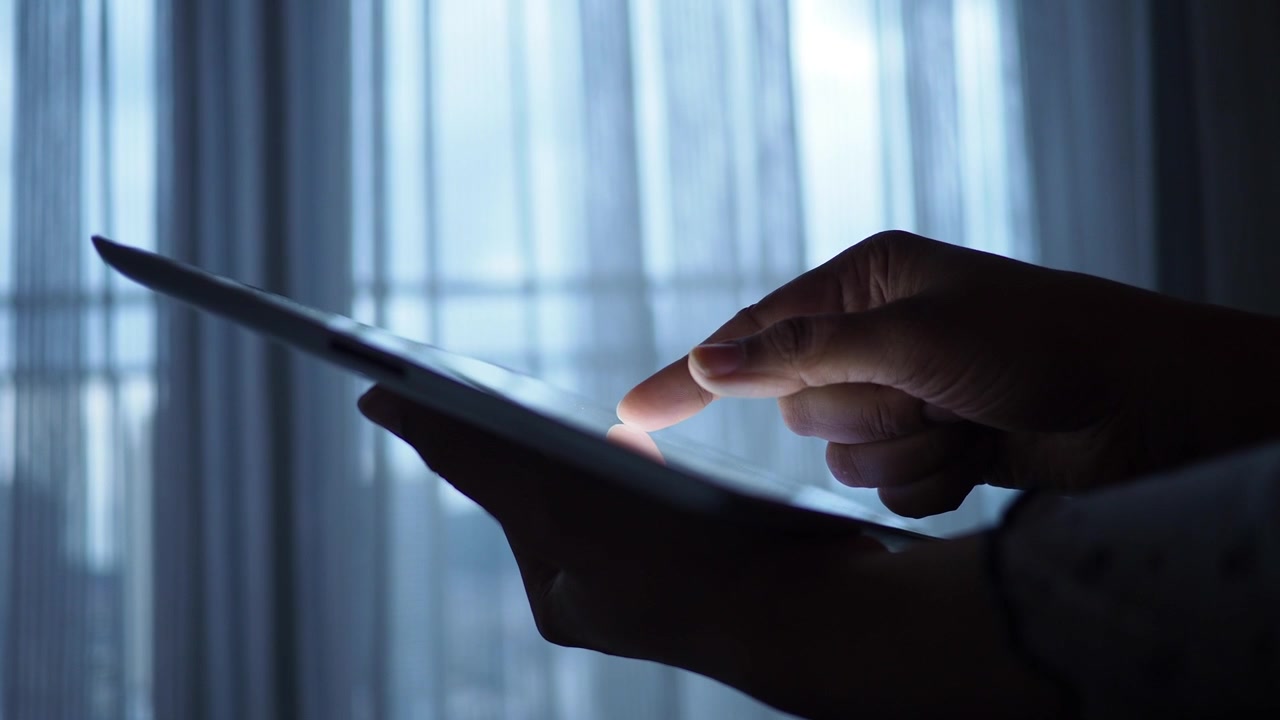 Person der bruger en digital tablet i et svagt oplyst rum