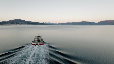 Drone-tracking-shot-behind-commercial-vessel-cruising-in-arctic-at-polar-night