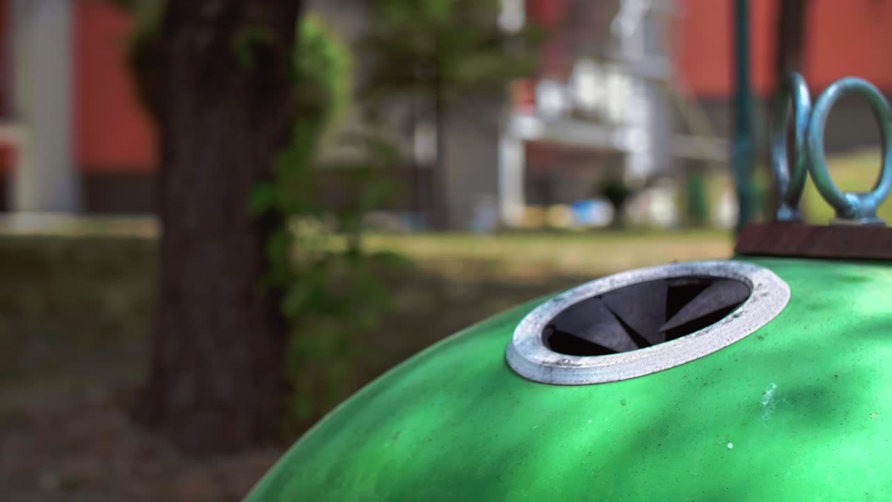 Man's hand throwing away empty, glass bottle in recycling bin
