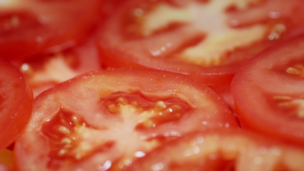 Round slices of ripe tomato rotate slowly.