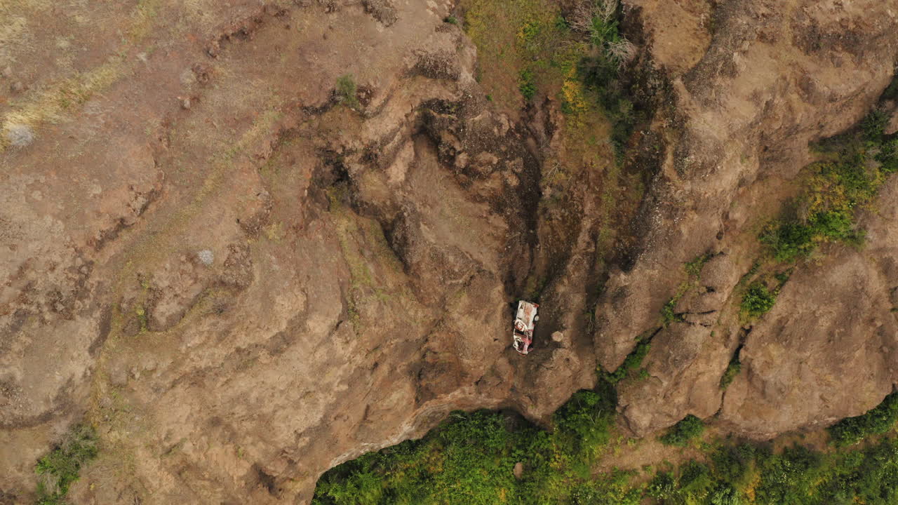 Top-down drone view flying over the edge of a tall rock cliff with shrubs and bushes at the bottom at the Butte Creek Canyon lookout