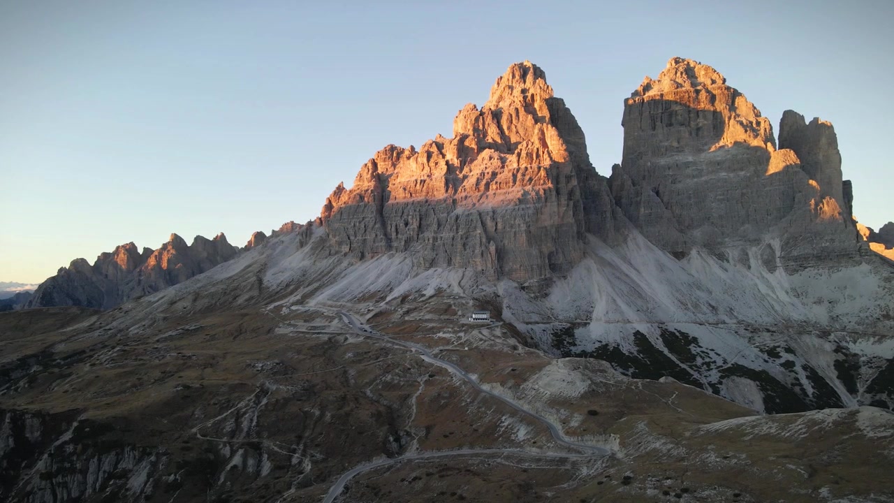 Una vista mozzafiato delle Tre Cime di Lavaredo in Alto Adige, Italia, con le sue vette imponenti circondate da aspri paesaggi alpini, cieli sereni e un'atmosfera di incontaminata bellezza naturale.