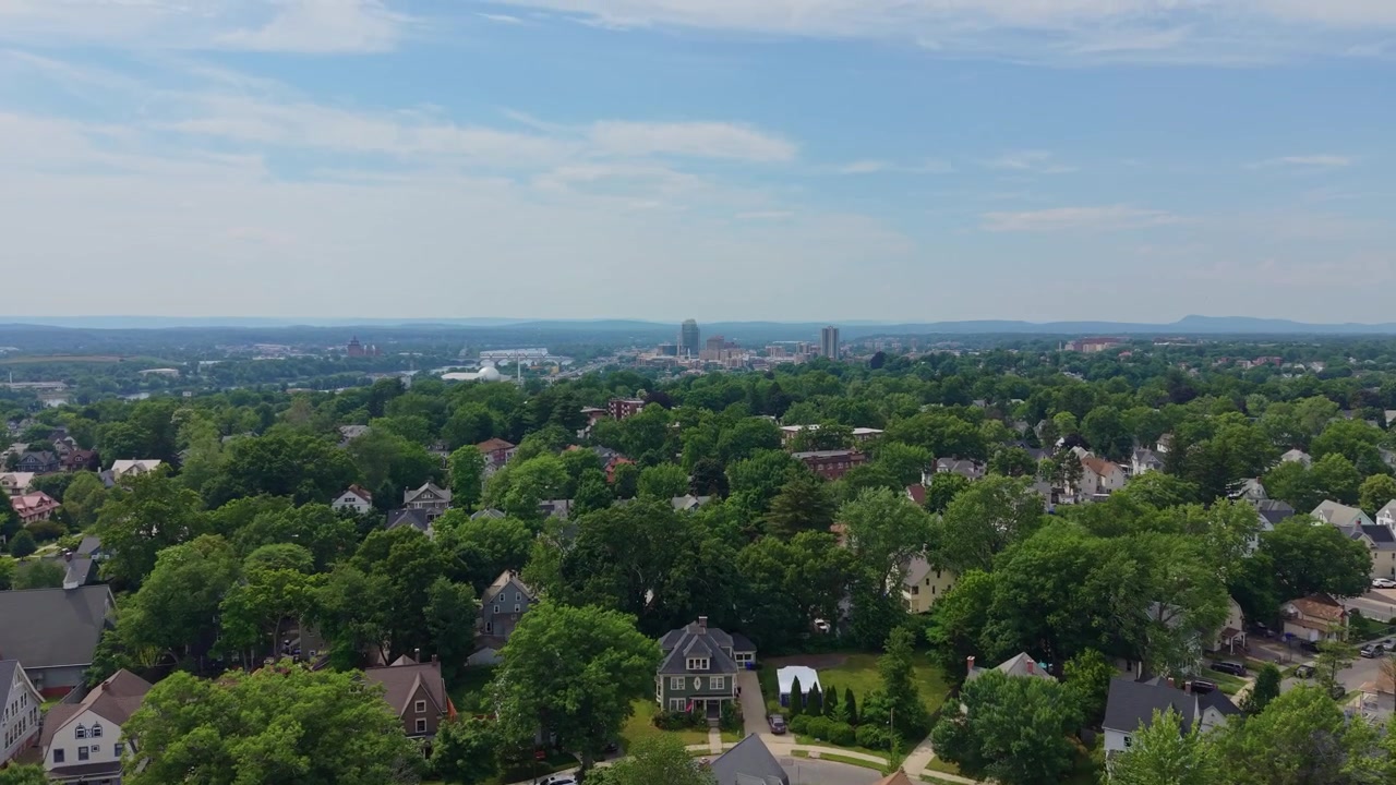 Barrio Residencial Con Casas, Iglesia Y Árboles Densos En Springfield, Massachusetts, EE. UU. Inclinación ascendente de dron, toma amplia