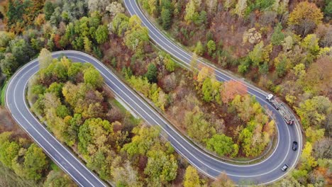 Timber-cargo-transit-truck-on-desolate,-distant-road-thoroughfare-in-autumn-woods