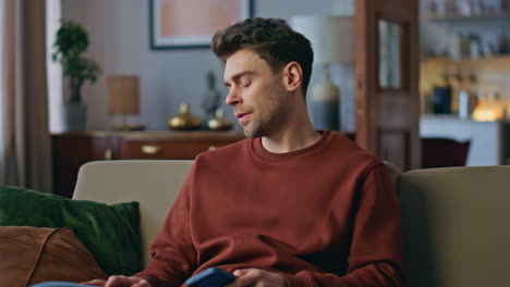 Disappointed freelancer reading smartphone message on apartment sofa close up
