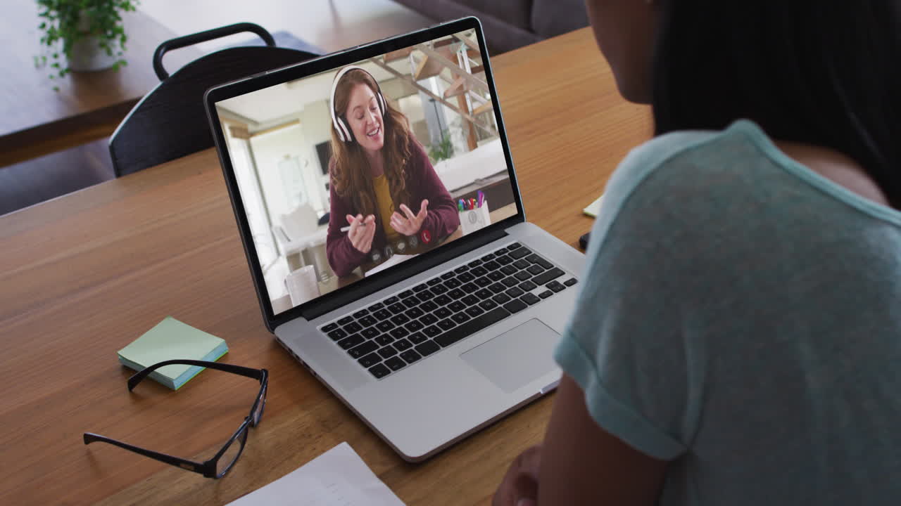 Biracial businesswoman sitting at desk using laptop having video call with female colleague