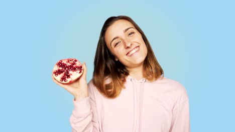 uma mulher sorridente e bonita segura uma romã cortada.