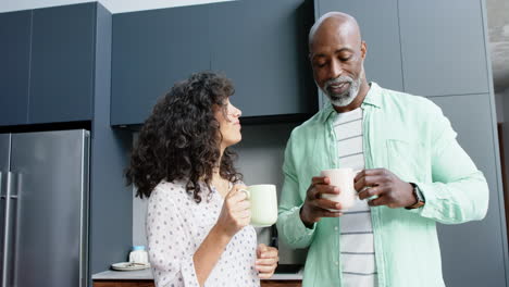 Glückliches-Biracial-Paar,-Das-In-Der-Küche-Redet-Und-Kaffee-Einschenkt,-Zeitlupe