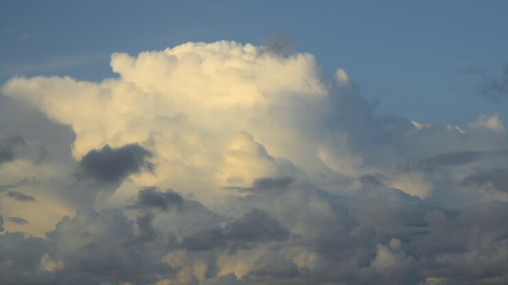 Large cumulonimbus cloud billowing in evening sunlight before becoming obscured by dark foreground cloud