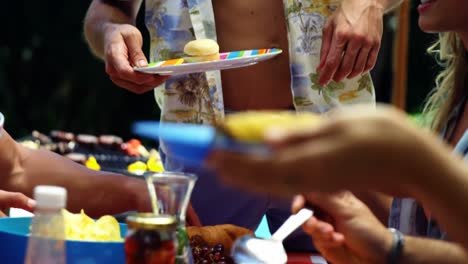 group of friends having meal at outdoors barbecue party