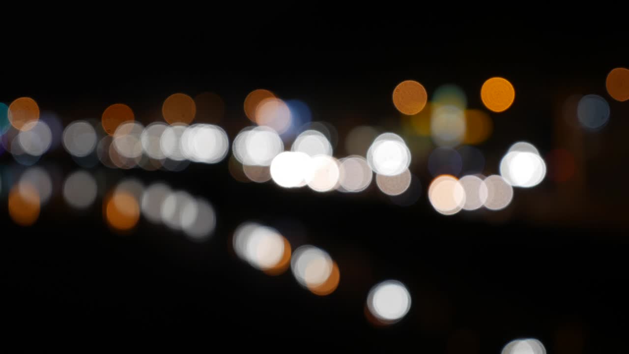 hermoso bokeh brillante en el fondo oscuro borroso por la noche. el redondo bokeh colorido brilla de las luces de los coches en la calle de la ciudad. fuera de foco con borroso. luces de la ciudad sin enfoque. bokeh de tráfico. concepto abstracto