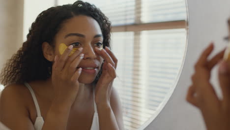 mujer aplicando parches de oro en los ojos