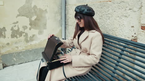 woman sitting on the bench opening the bag with the vintage camera