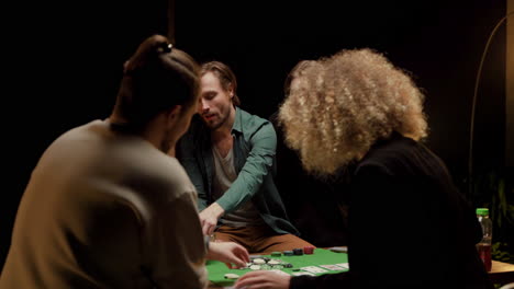 rear view of group of friends playing poker sitting on chairs at a table at home 1