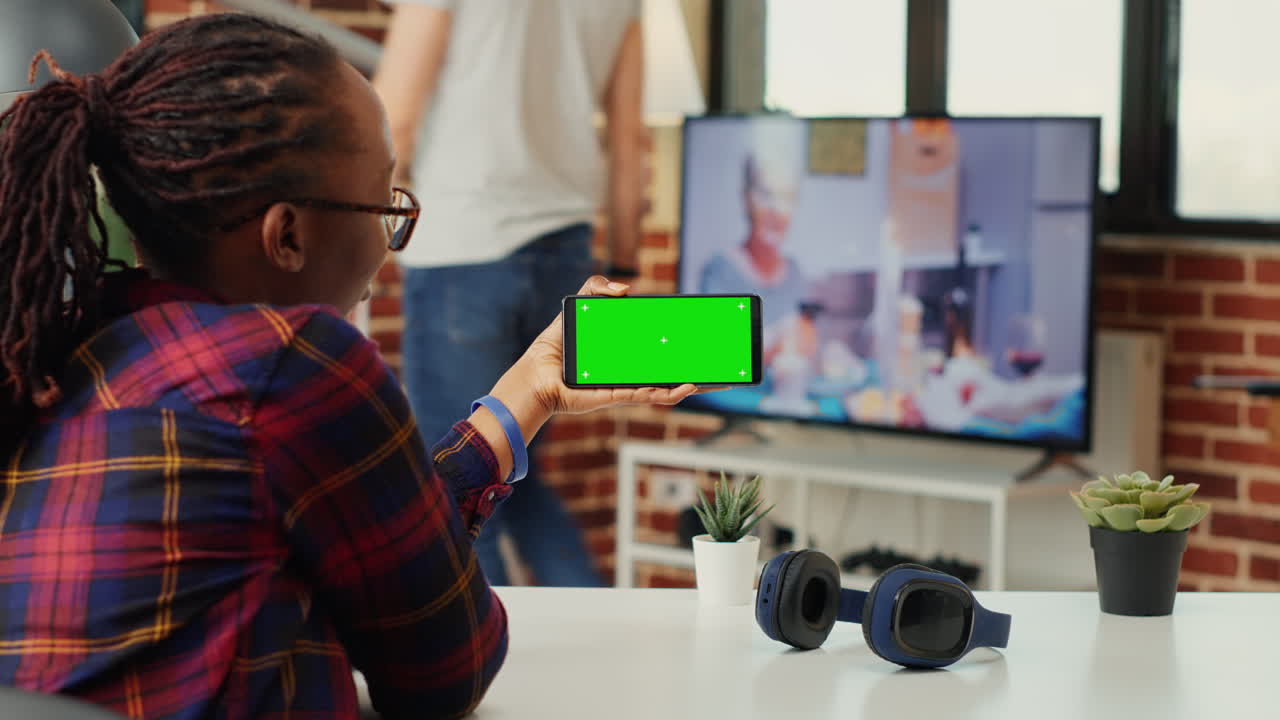 Female freelancer looking at smartphone with greenscreen