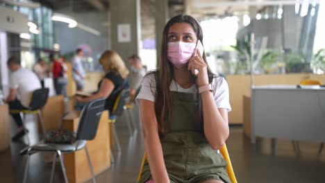 teenager waiting in a medical office, wearing a mask, talking on the phone