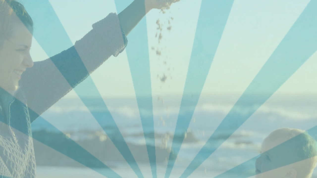 Playing on beach, woman and child enjoying animation with blue sunburst pattern