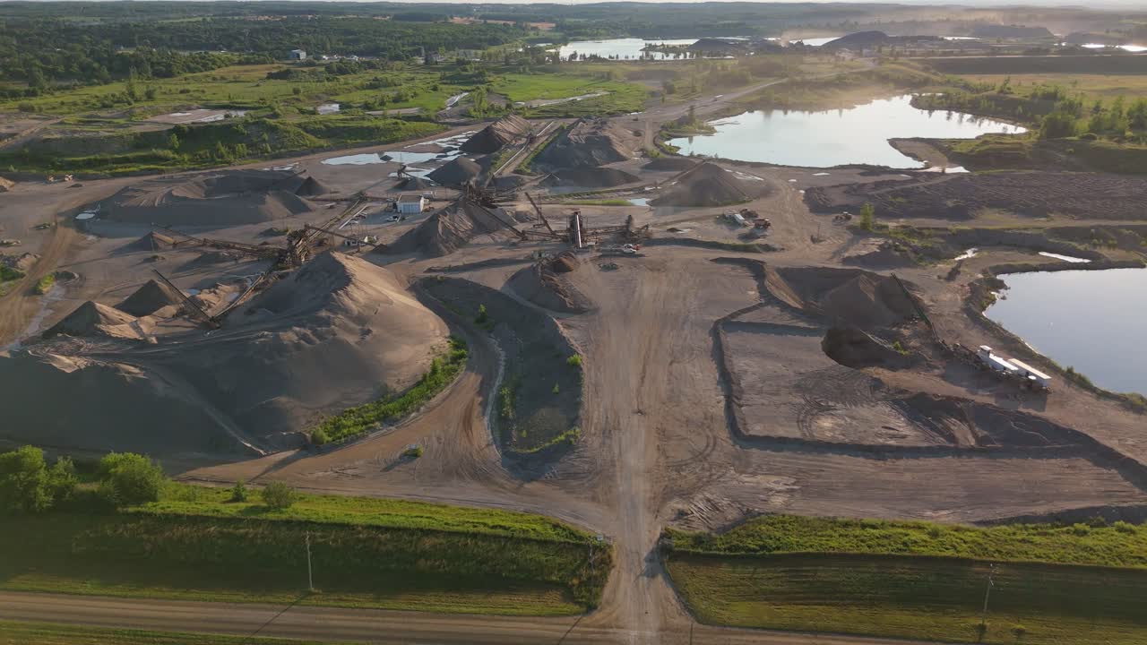 Aerial establishing along road into gravel pit quarry with sand piles and access roads in Caledon