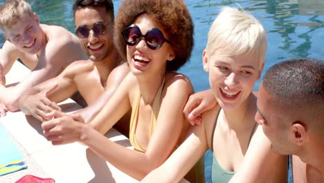 glückliche, vielfältige freunde, die im sommer bei einer poolparty im wasser reden