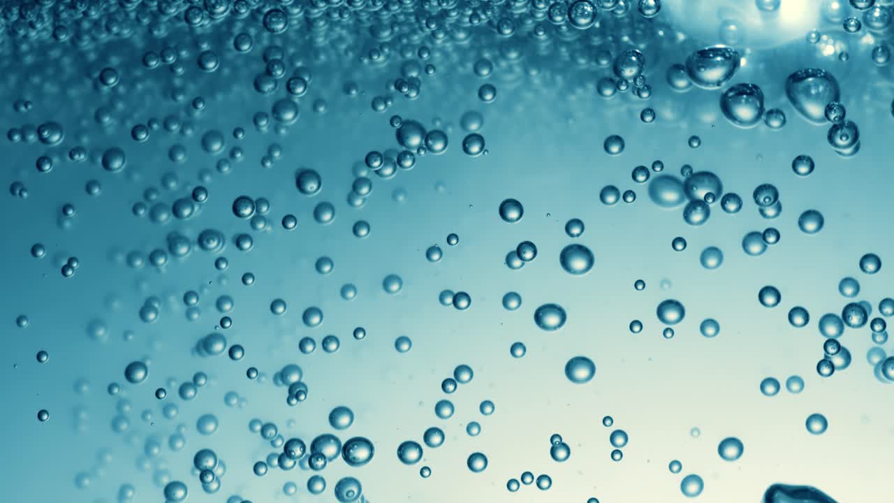Many water bubbles in blue water close up, abstract water wave with bubbles in slow motion