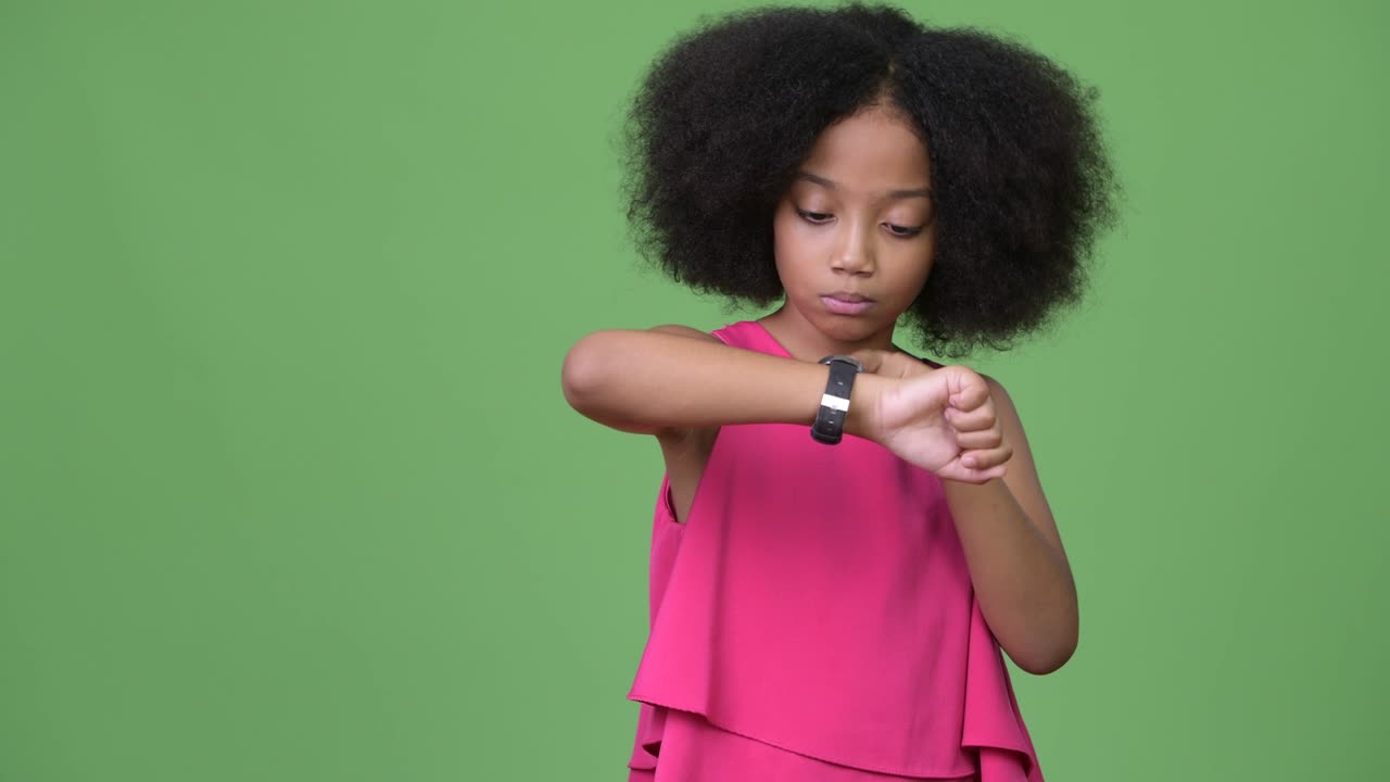 una joven africana con cabello afro comprobando la hora.