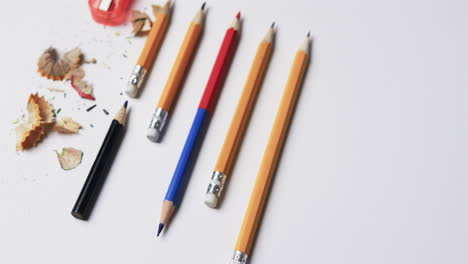 close up of pencils and pencil sharpener on white background, in slow motion