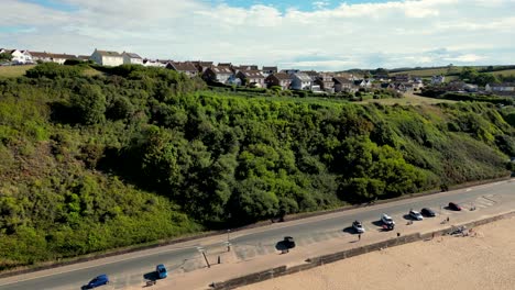 Parallaxe-Drohneaufnahme-Der-Marine-Drive-Promenade-Am-Strand-Von-Exmouth,-Devon,-Die-An-Einem-Klaren,-Sonnigen-Morgen-Das-Wohngebiet-Des-Schützenlochhügels-Auf-Der-Spitze-Des-Hügels-Enthüllt