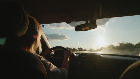 conductora de mediana edad conduce un automóvil al ponerse el sol 1