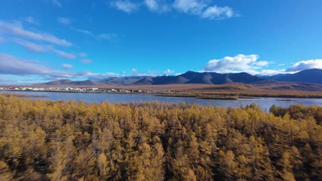 aerial view of a calm river surrounded by autumn foliage and mountains