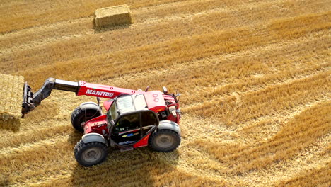 tractor collecting bales of hay. aerial view of tractor colecting on agricultural field