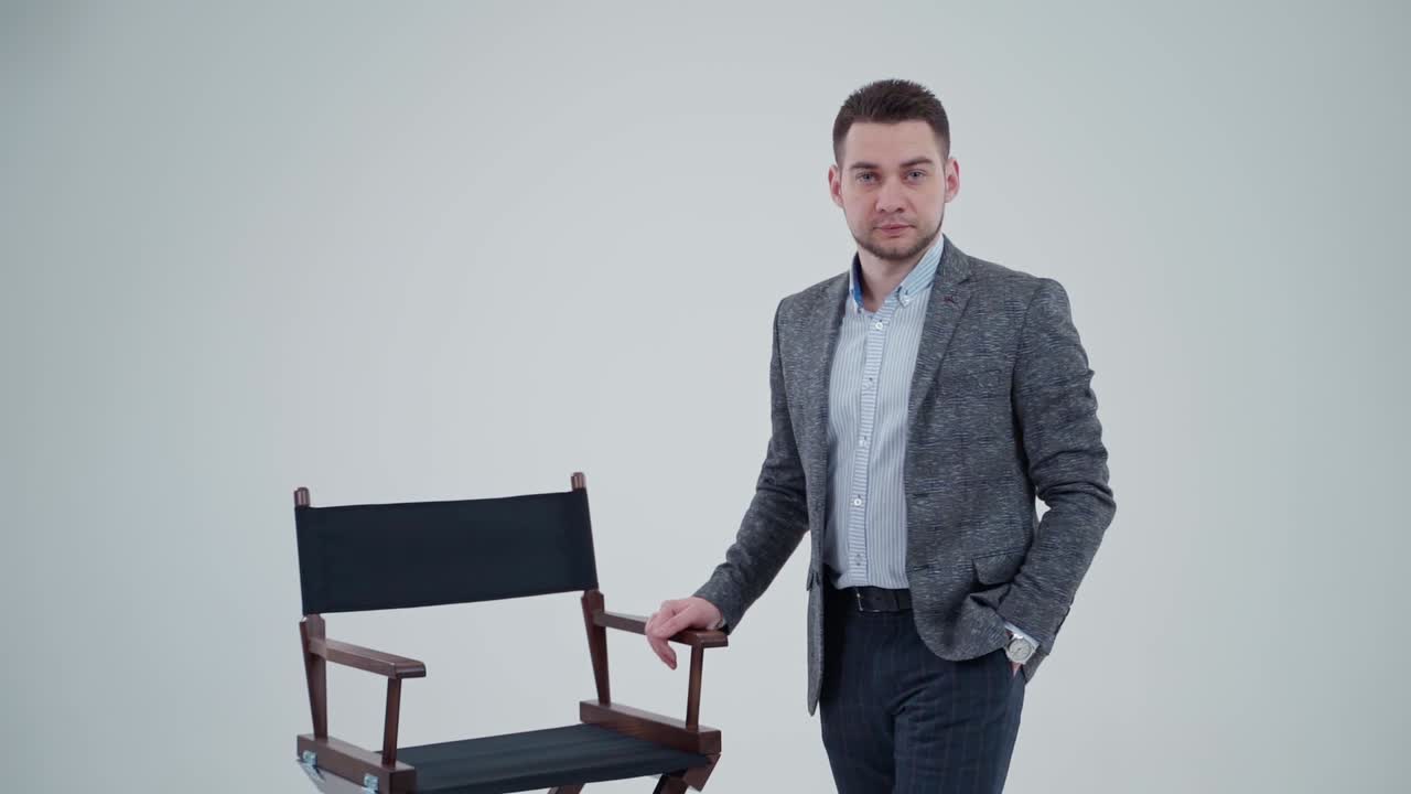 Portrait of a stylish man in suit in studio. Handsome businessman in grey costume isolated on light background. Slow motion.
