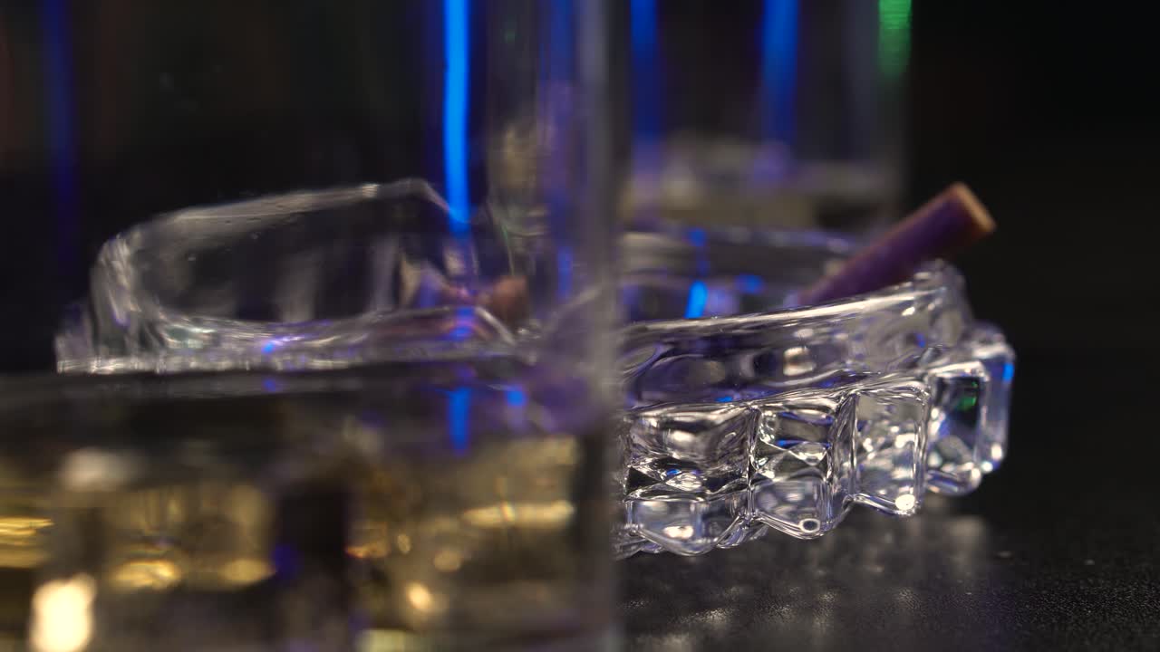 Sigarette in un pub o un bar, posacenere e bicchieri da whisky, primo piano