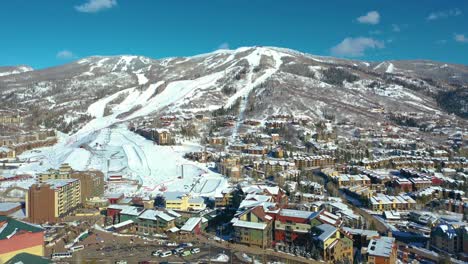 drone flying backwards from the city of steamboat springs colorado through beautiful ski resort at winter