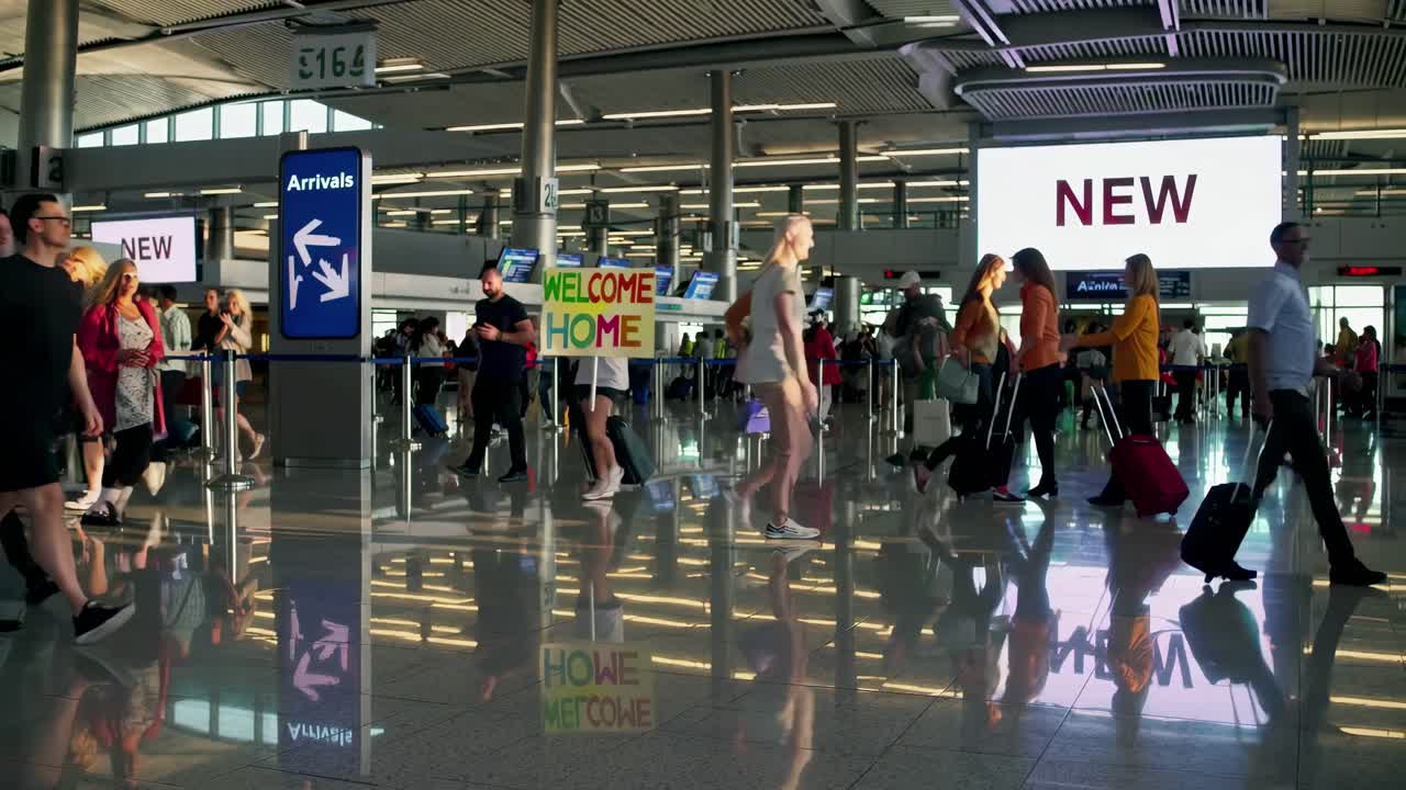 Wide-angle shot of a bustling airport terminal with travelers and digital screens