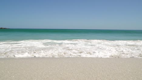 cámara lenta de romper las olas en la playa que fluye directamente a la cámara