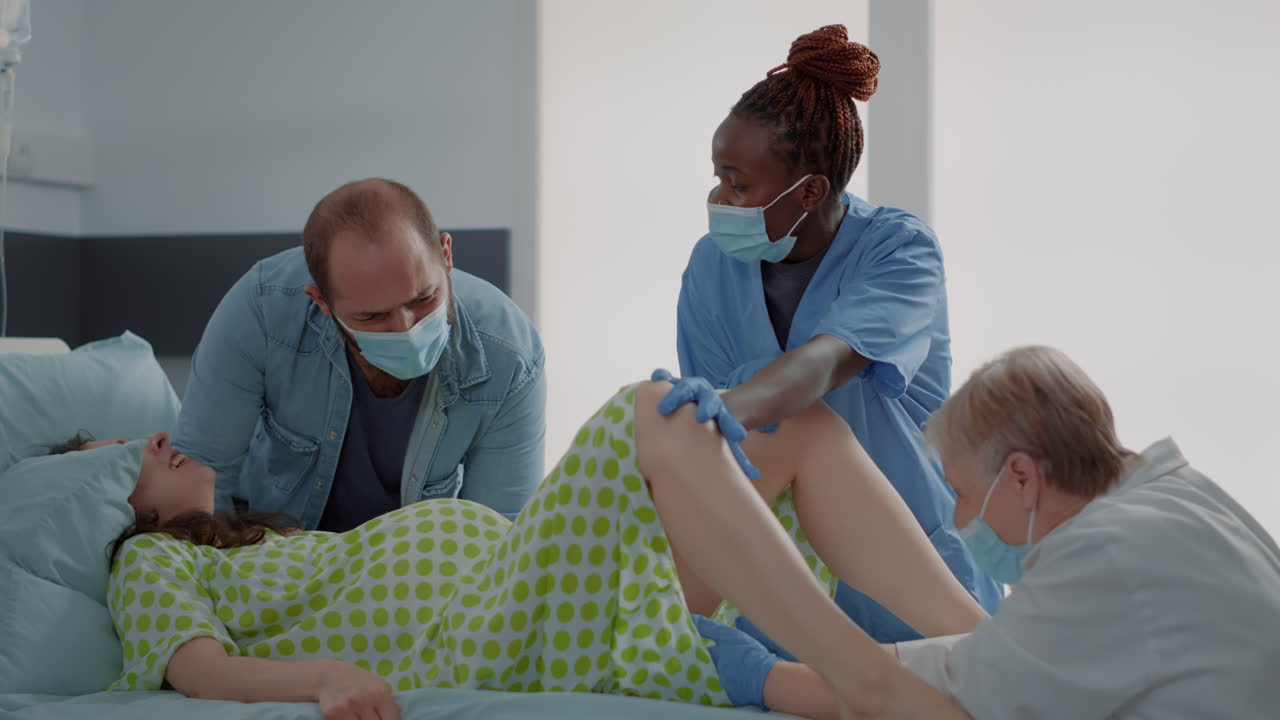 Multi ethnic people delivering child in hospital ward