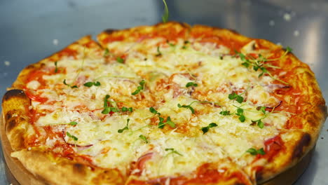 cook decorates ready pizza. chef's hand in glove is sprinking fresh green sprouts on a baked pizza in a restaurant. close-up.