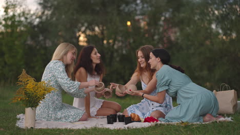 a group of young attractive women in nature in an open area sculpt from clay discuss the results of the lesson communicate share their impressions laugh rejoice at the results.