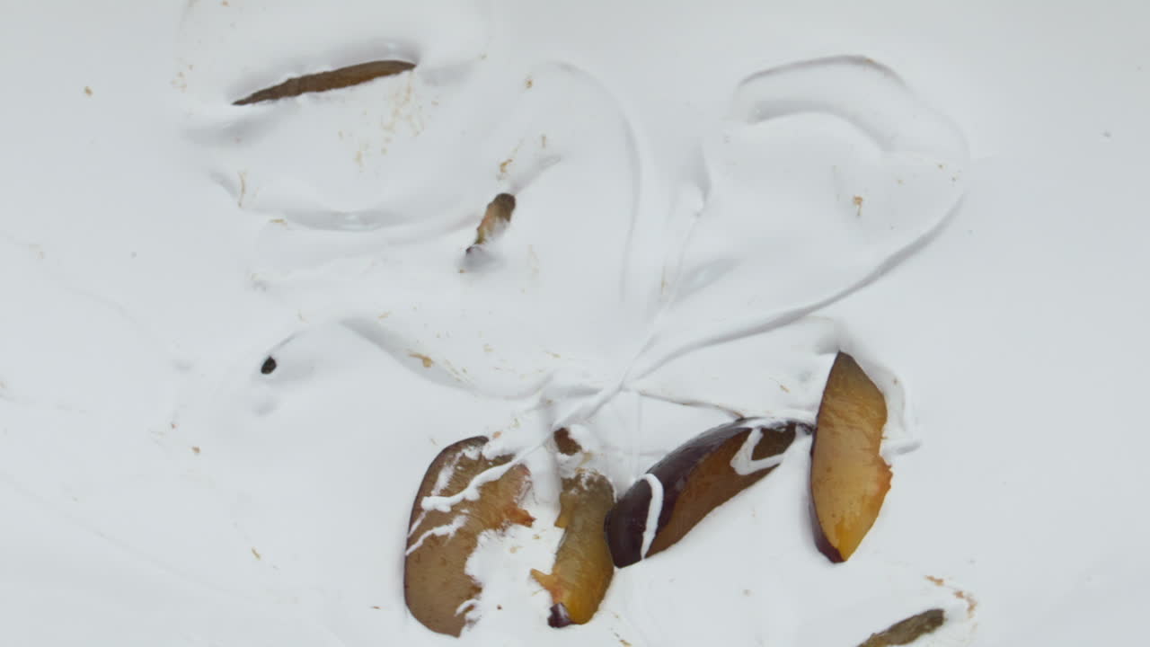 зрелая сочная слива падает йогурт в супер медленном движении близко. домашний десерт.