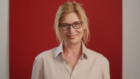 mujer mayor alegre posando sobre un fondo rojo en el estudio